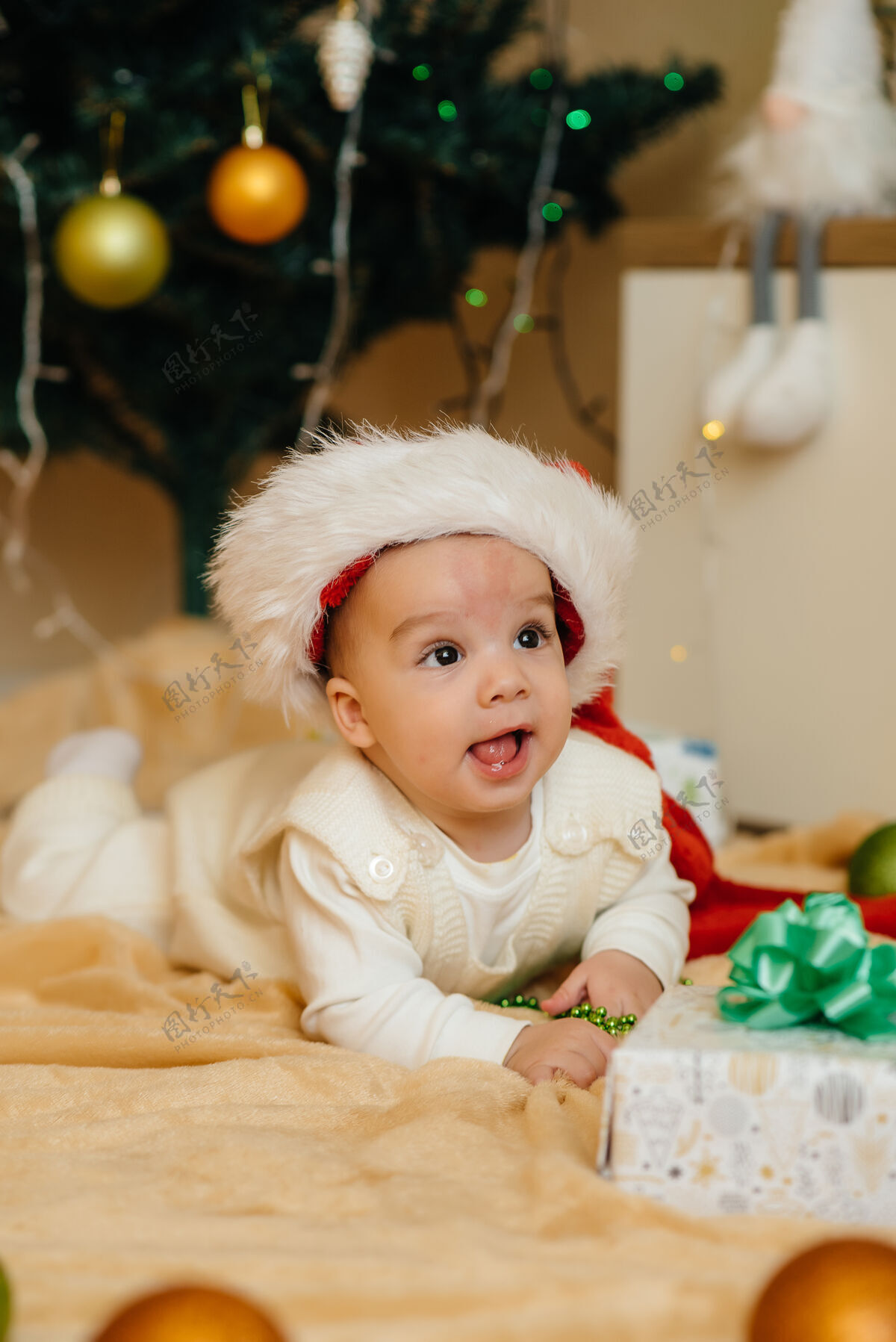 圣诞树可爱的微笑着的婴儿躺在圣诞树下和孩子们玩耍礼物.圣诞节还有新年庆祝活动房间年杉木