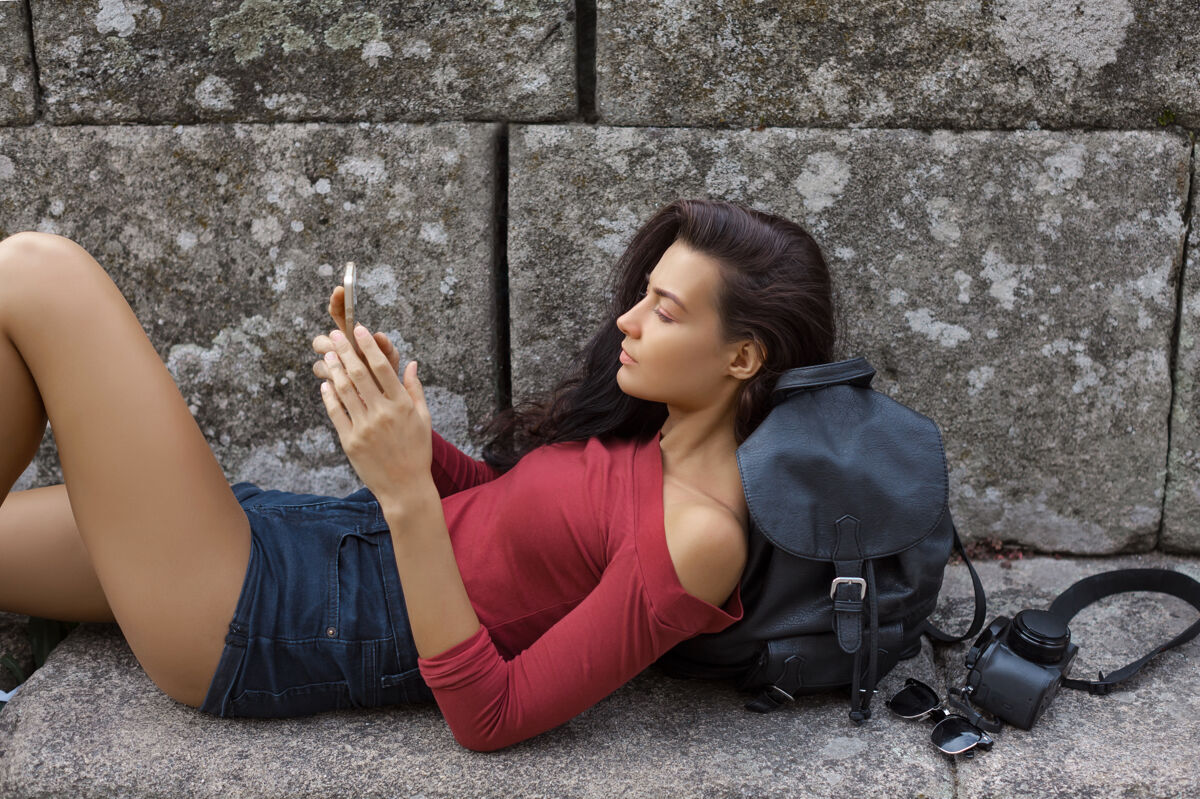旅游带着智能手机背包和相机的年轻女孩户外穿便服的女人学生女人手机