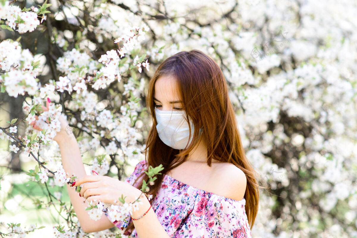 春天在樱花盛开的樱花树下 一个穿着白色上衣 戴着冠状病毒花朵面具的温柔女孩的特写镜头流行病开花自然