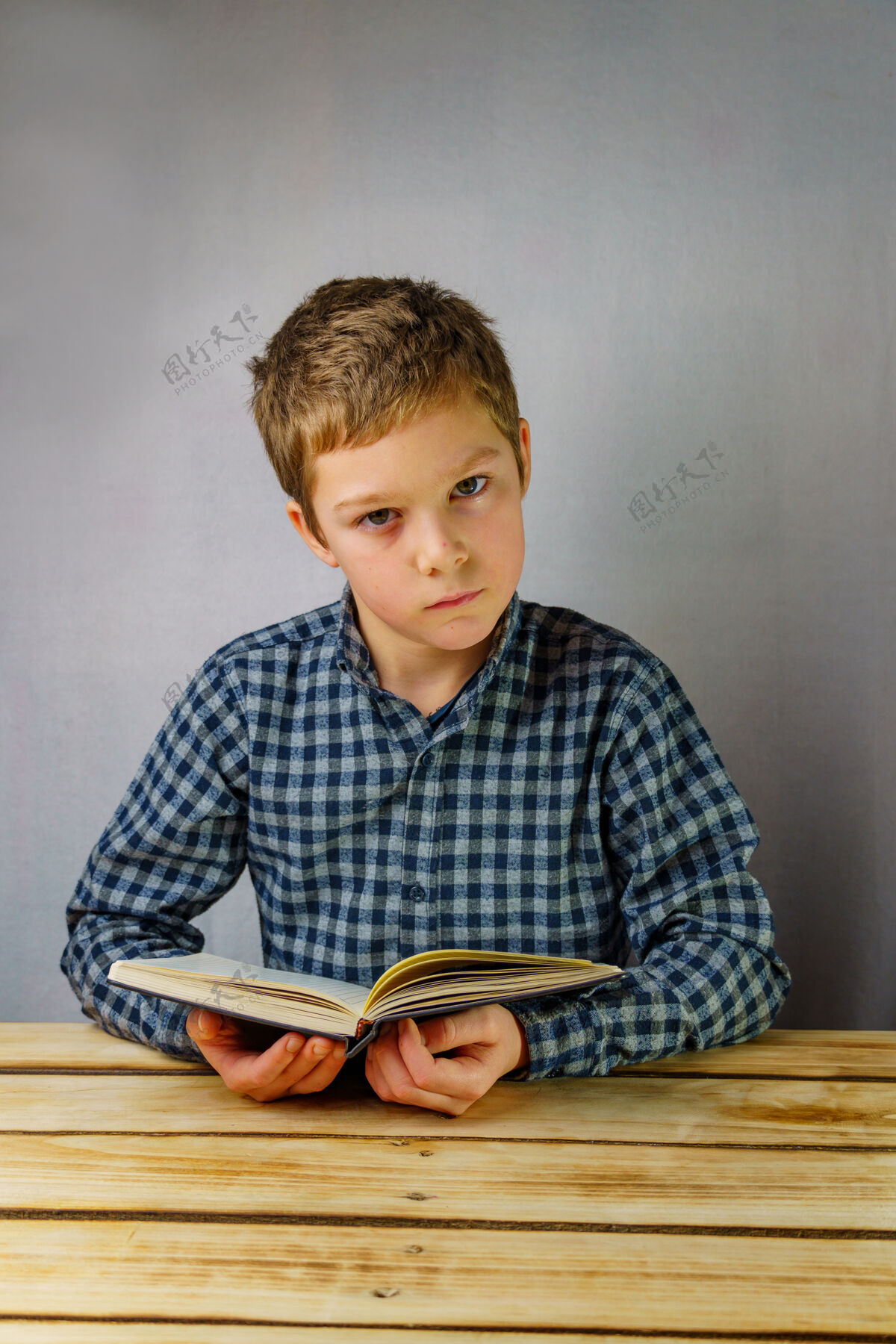 书籍穿着格子衬衫 手里拿着一本书的严肃男孩手垂直照片 学生打开兴趣
