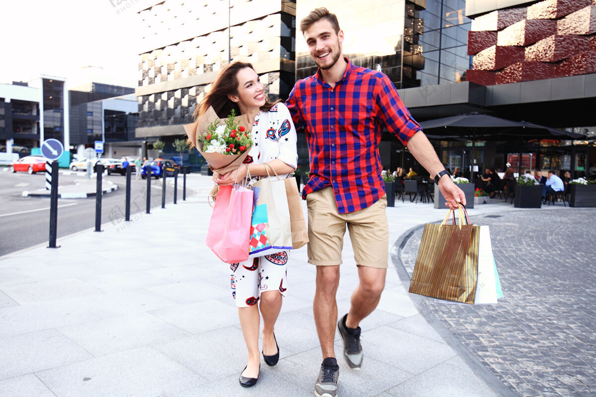 女性带着购物袋的年轻幸福的一对城市商业休闲