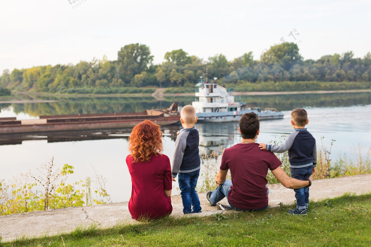 孩子亲子 童年和自然的概念-一家人坐在绿色的土地上 看着小男人爱父亲