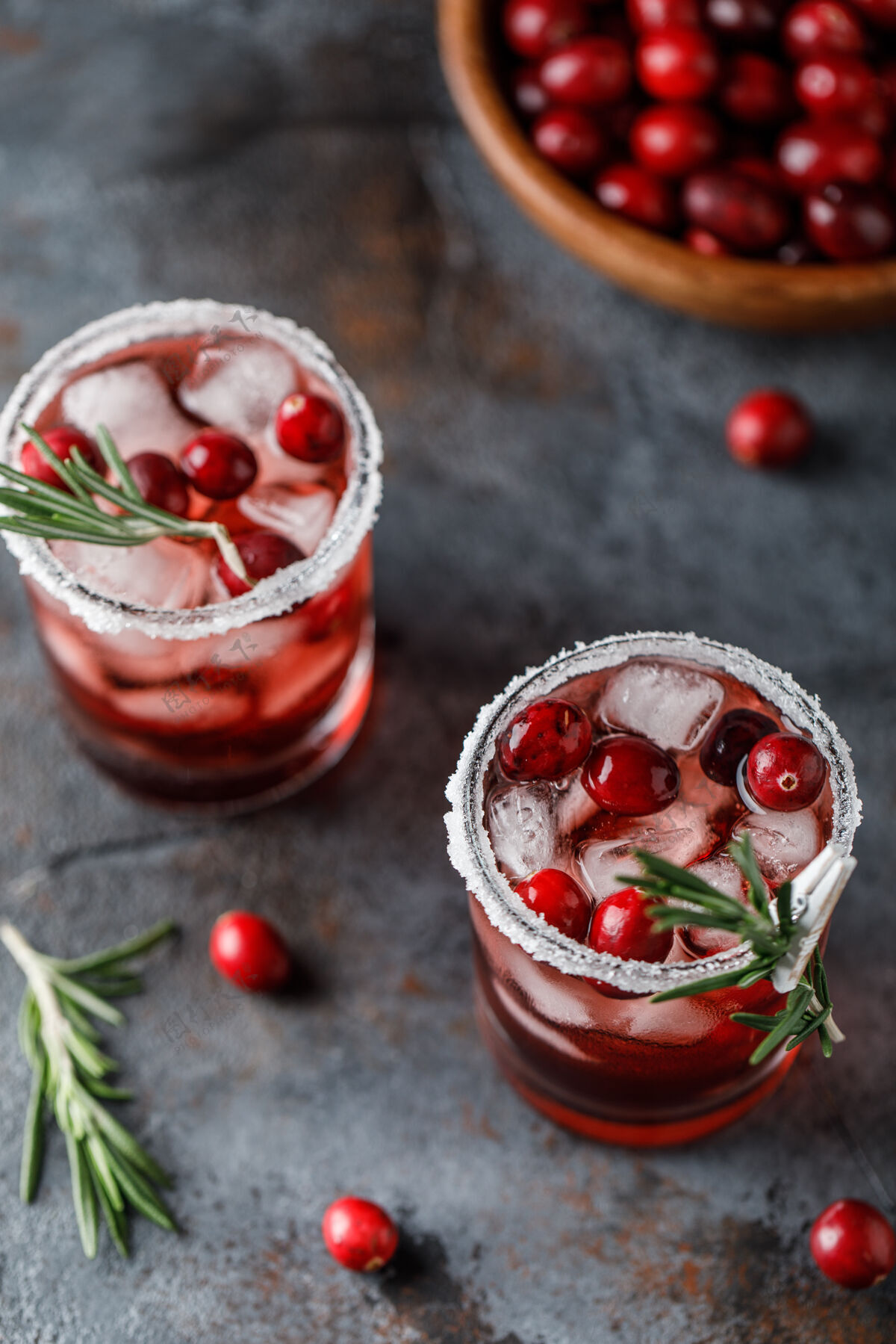 冷红莓鸡尾酒冰圣诞节红莓饮料在玻璃装饰糖和迷迭香冰凉圣诞节
