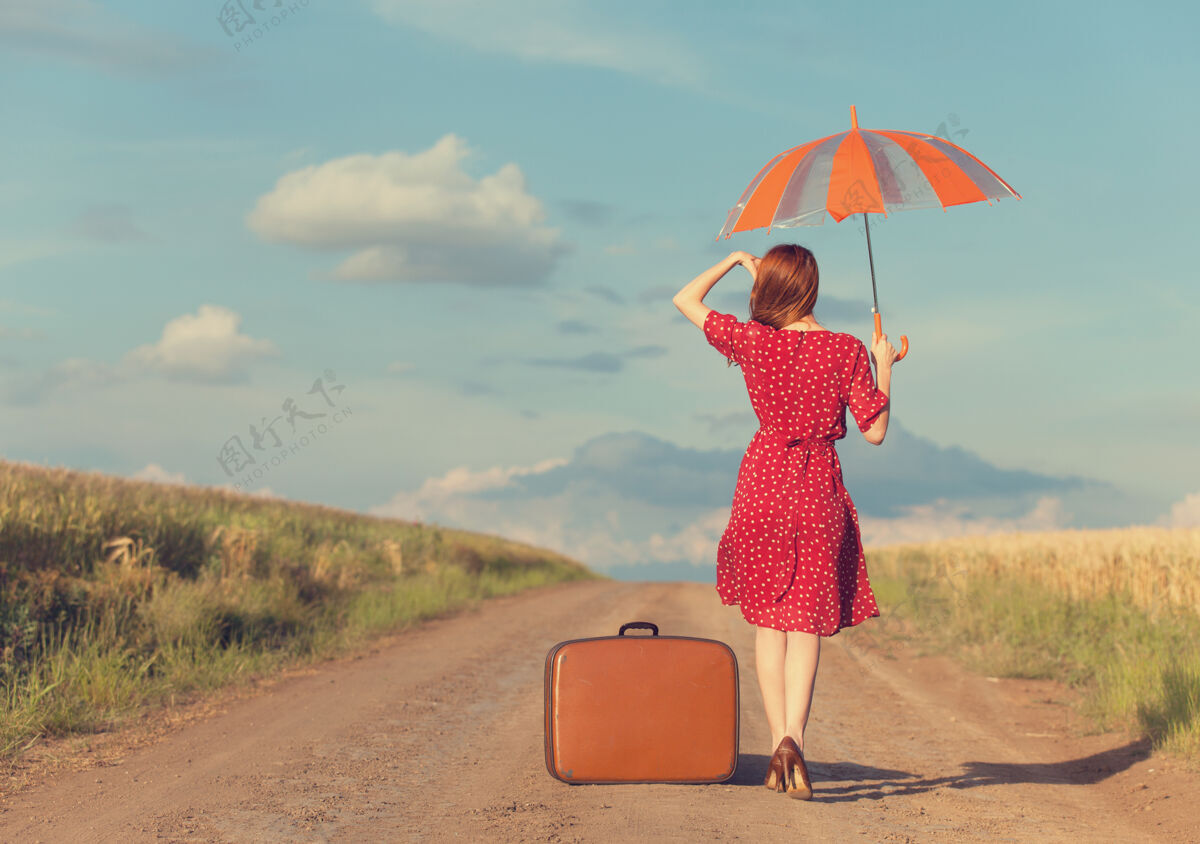 红发在户外带着雨伞和手提箱的红发女孩孤独乡村保持