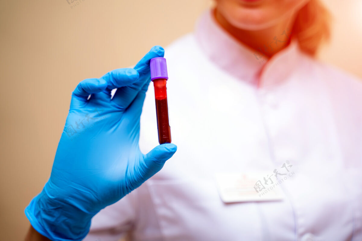 医院戴着蓝色手套的医生手里拿着一根装有血样的管子医疗测试分析