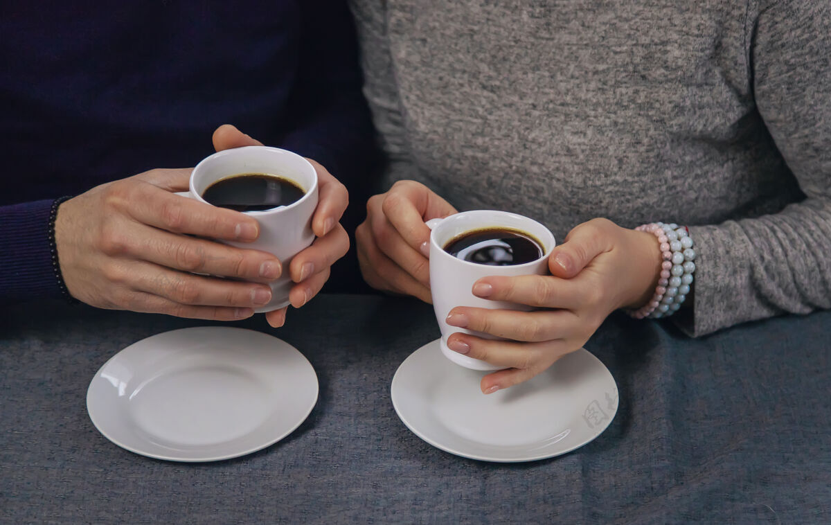 交谈一男一女端着一杯咖啡坐在桌边手心男性