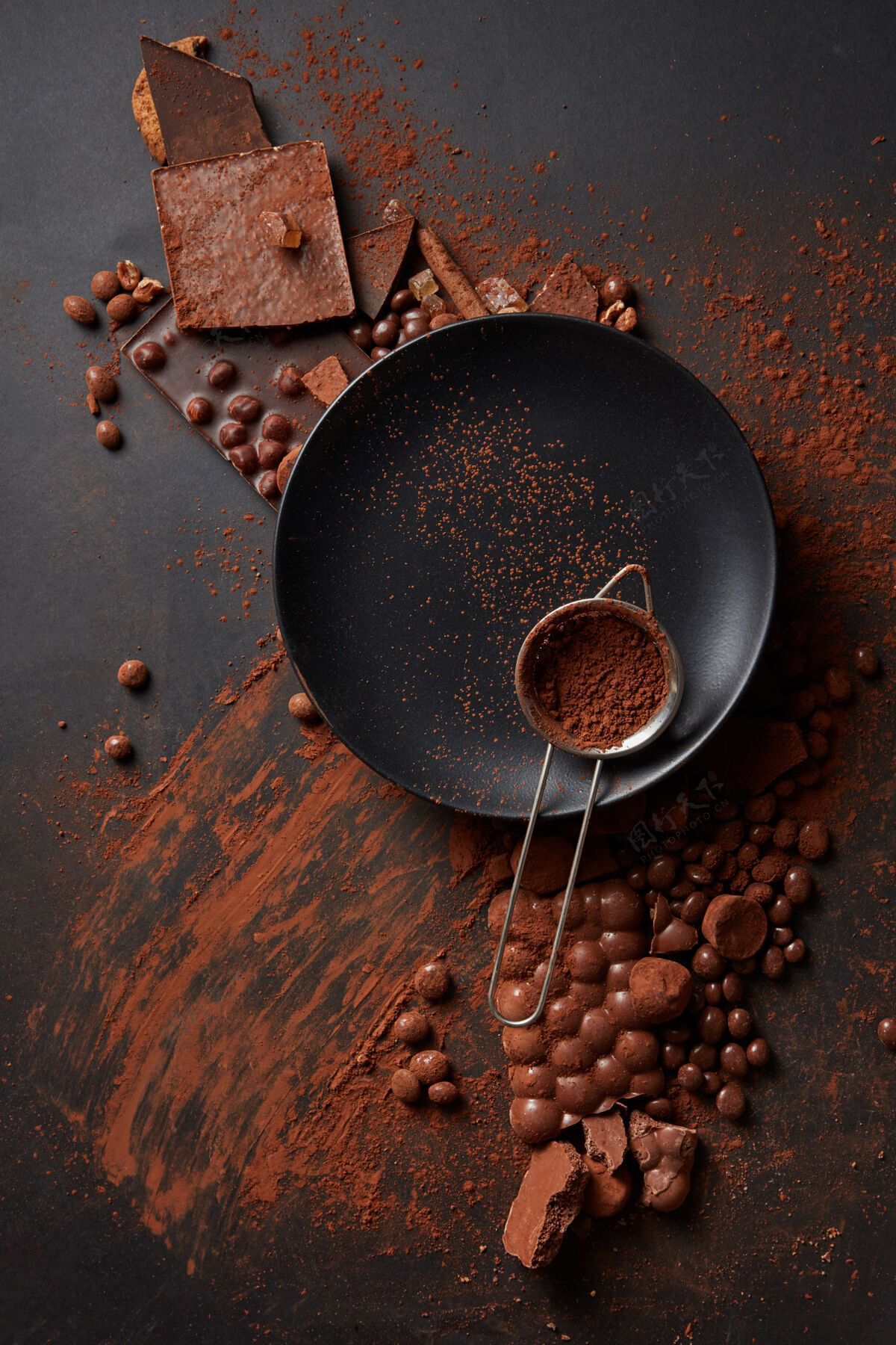 肉桂可可粉放在黑盘子上的筛子里 黑的表面有巧克力可可盘子片剂