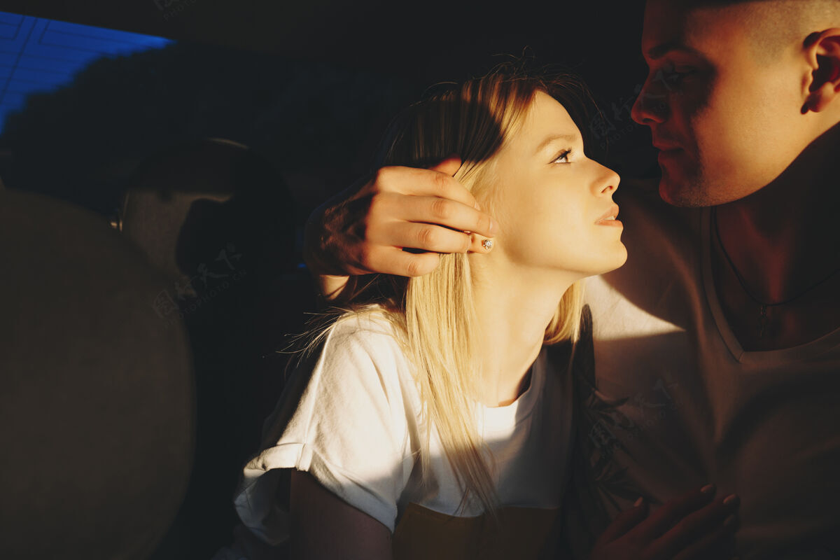 春天一个可爱的金发女人被她的男朋友拥抱的特写镜头 同时看着坐在他们车里的另一个朋友沥青阳光