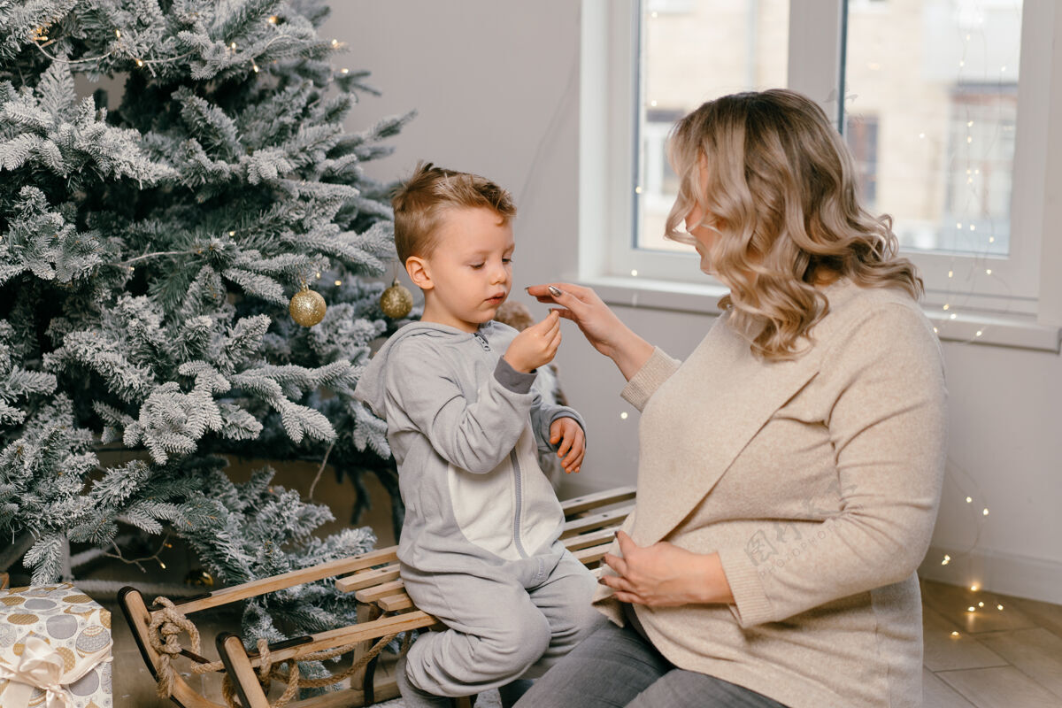 装饰节日圣诞节白种人妈妈和可爱的小儿子在家里装饰圣诞树玩家庭传统圣诞树冬天孩子