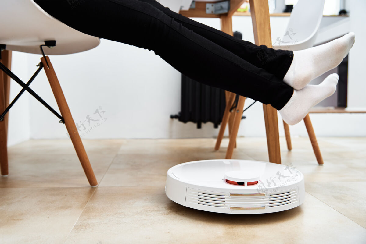 房子机器人吸尘器与家具一起在地板上工作 而女人休息现代智能家居清洁机器刷子