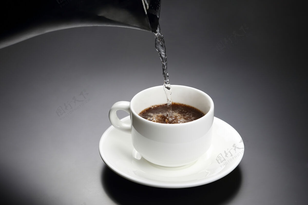 液体把开水倒进一个白杯子里 再加上一个黑杯子咖啡热的喝酒咖啡因热的盘子