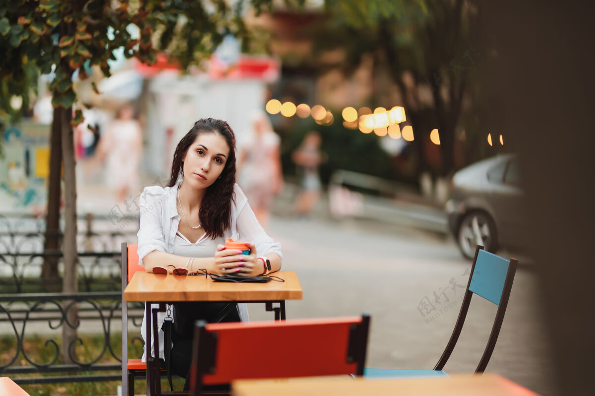 沟通坐在桌子旁的女人街道晚上温暖的城市高中高质量的照片城市趋势女性
