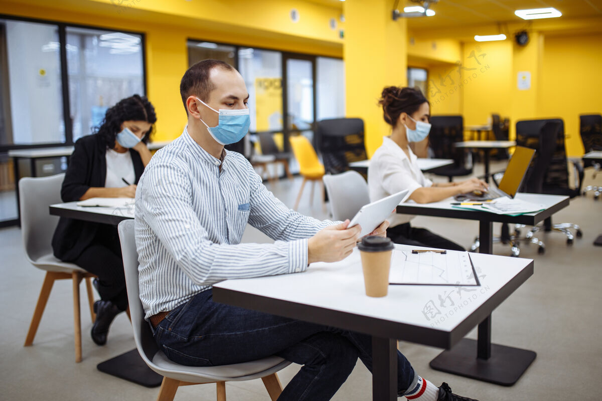 女性三位同事在办公室里一起工作 戴着医用口罩保持着社会距离病毒工人纸张