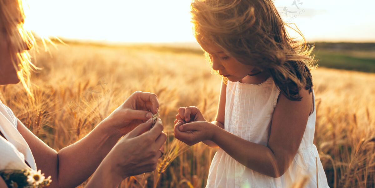 女孩日落时分 一位白人母亲和她的女儿在田里抱着一些小麦种子父母田地面包
