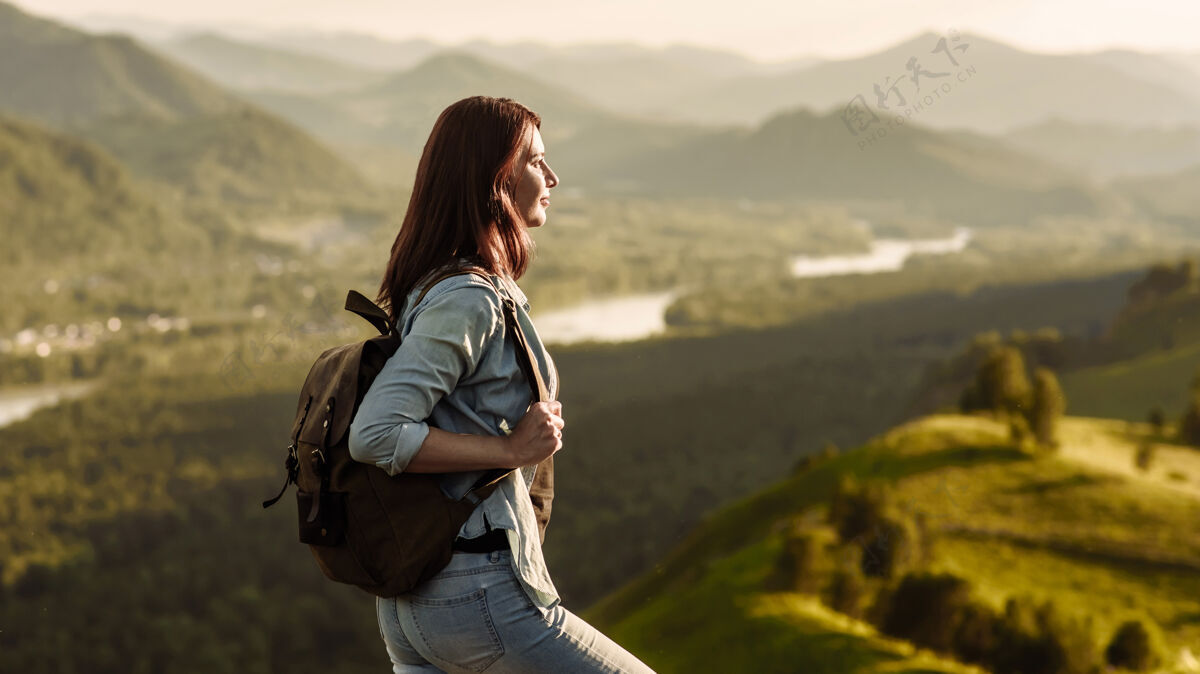 山一位背着背包的女徒步旅行者在旅行途中看到了大自然中山顶上的晨光假期.旅行和冒险的概念探索女性徒步旅行者