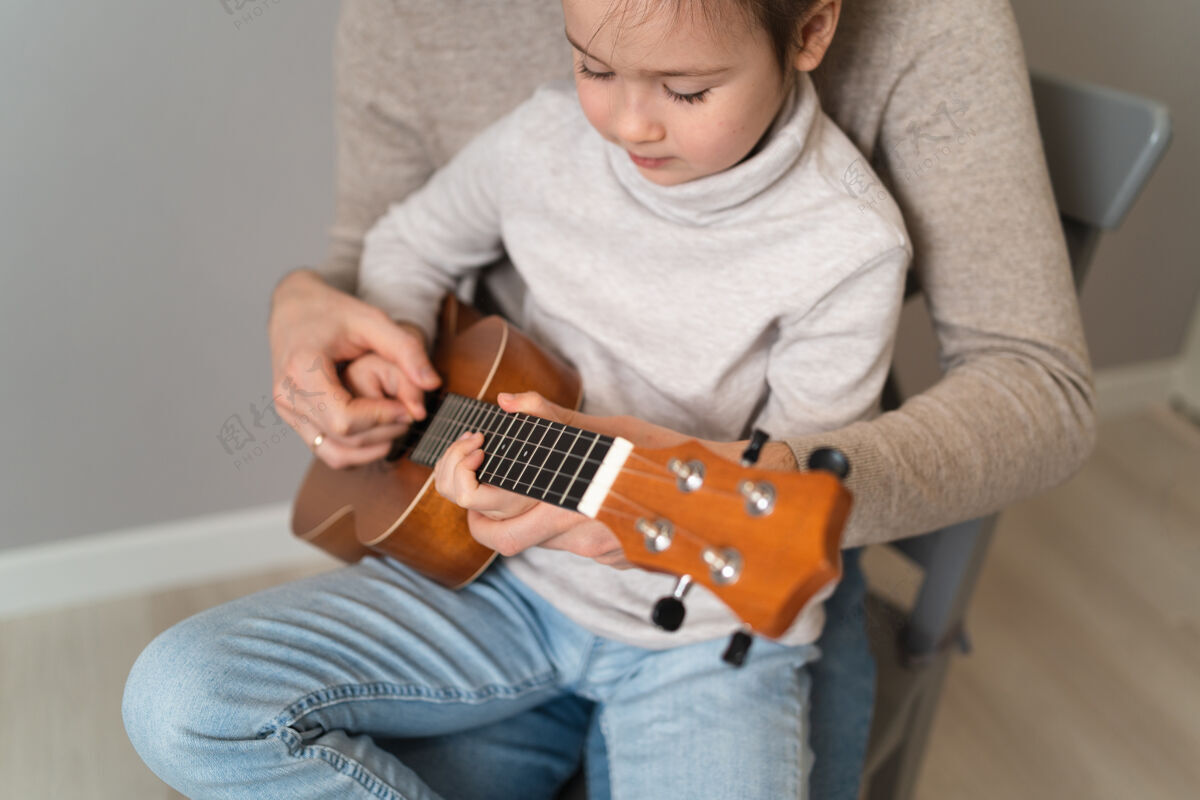 音乐爸爸用手弹吉他女儿孩子学会用钢琴演奏乐器音乐导师父亲和孩子的二重唱女孩乐趣可爱