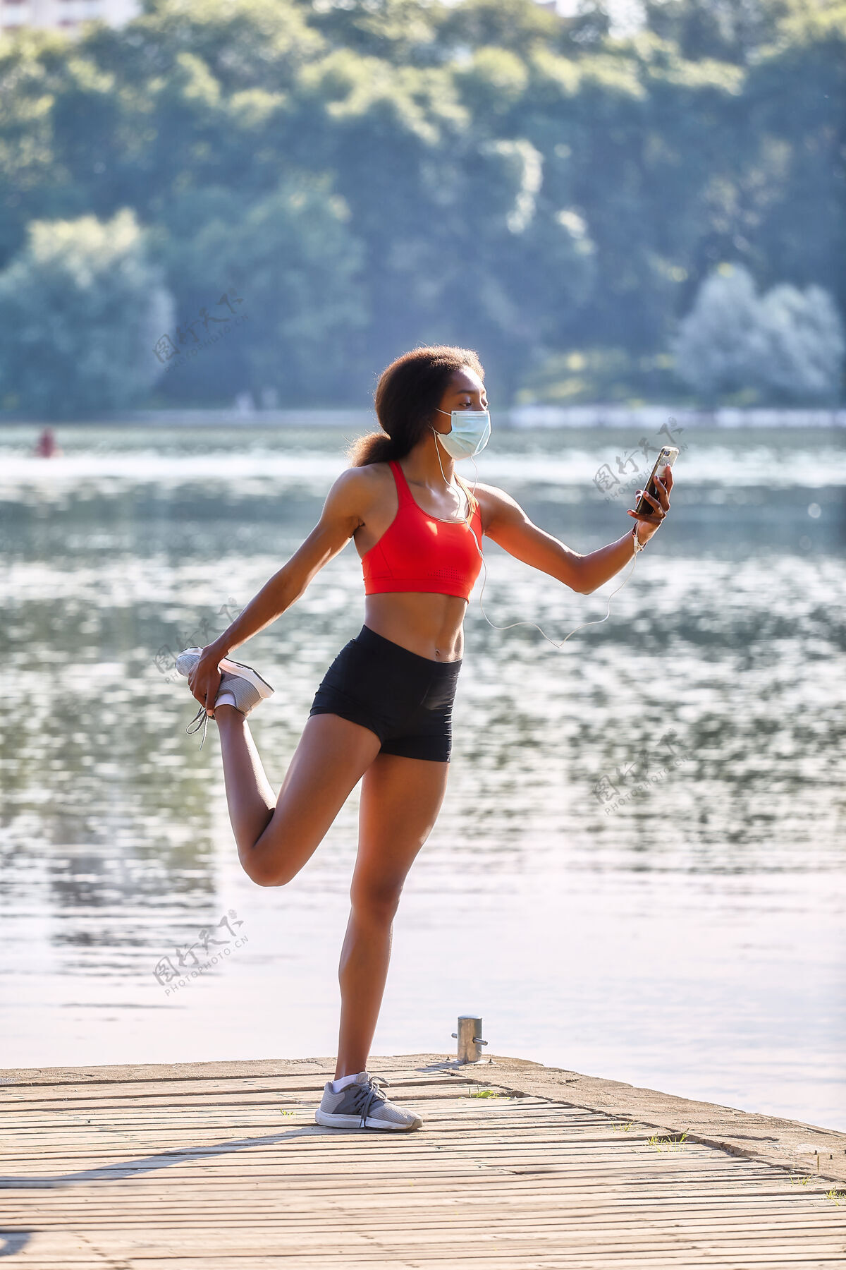 动作年轻的黑人女运动员早上在湖边的码头上进行训练森林健康水