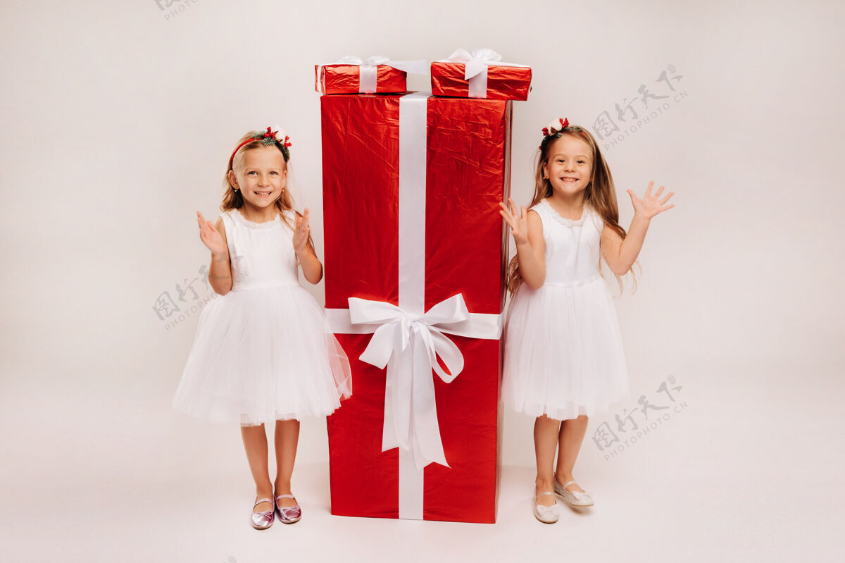 礼物两个小女孩拿着圣诞礼物 白色的和巨大的礼物孩子肖像童年