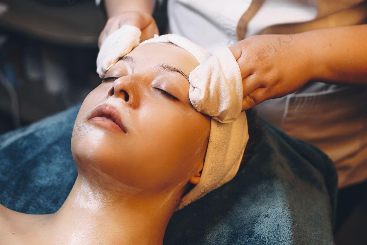 专业特写镜头：一位年轻女性在美容师的健康spa中进行面部治疗皮肤生活方式按摩