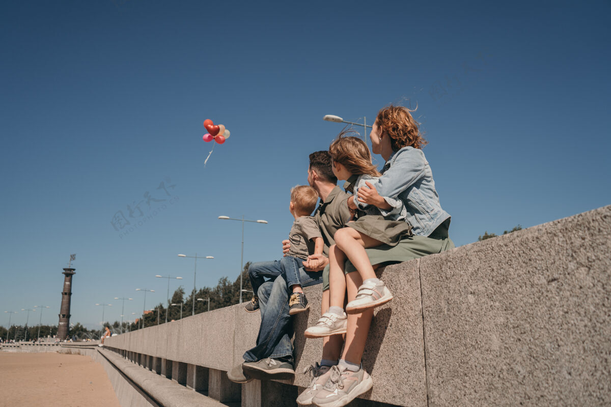 女人一张快乐的夏日艳照家庭父母带着孩子看气球舒适一家人在沙滩上散步男性宝贝气球