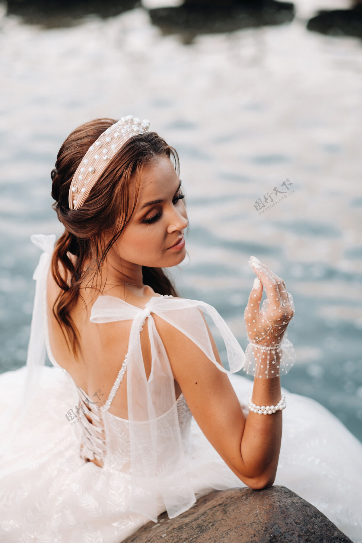 美丽一位穿着白色礼服 戴着手套 赤脚的优雅新娘正坐在公园的瀑布旁 享受着大自然新娘风景欧洲