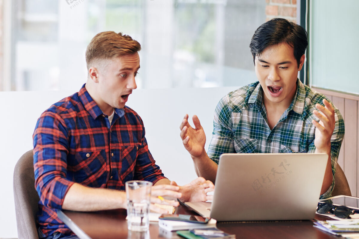合作年轻的创业者在笔记本电脑屏幕上阅读令人震惊的新闻情绪同事工作