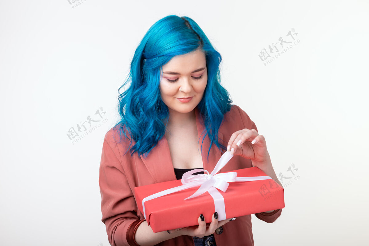 五颜六色人 节日和时尚的概念-快乐的年轻女子蓝色头发手持一个白色背景礼盒室内脸年轻