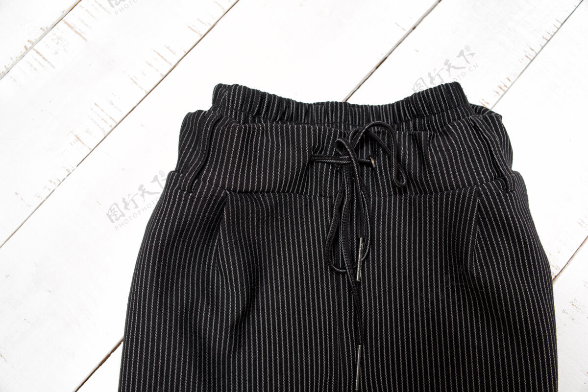 套装服装时尚概念.细节一条黑色的裤子搭在白色的木头上背景.top查看服装袖子假日