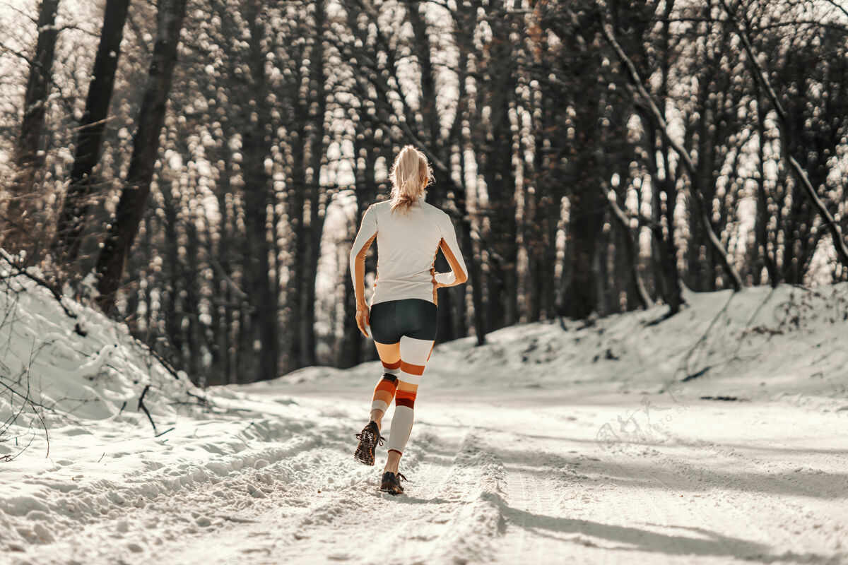 锻炼健身女运动员在雪地上跑步的后视图冬季运动 有氧运动 冬季健身运动装健康寒冷