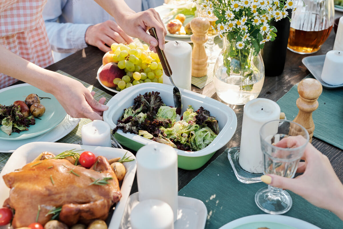宴会年轻女性的手拿着勺子 或是在节日餐桌上搅拌熟菜 与朋友们一起享用自制食物庆典自助餐蔬菜