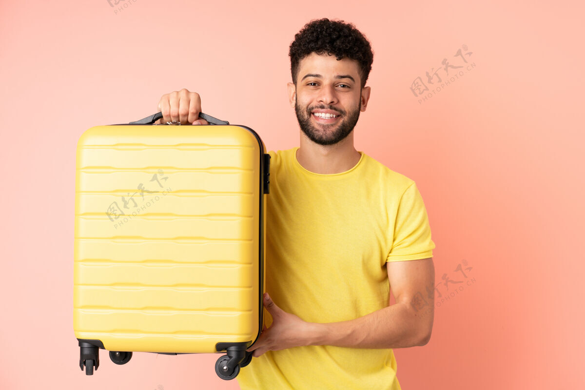 人年轻的摩洛哥人带着旅行箱在度假时被隔离在粉色背景下积极头发年轻