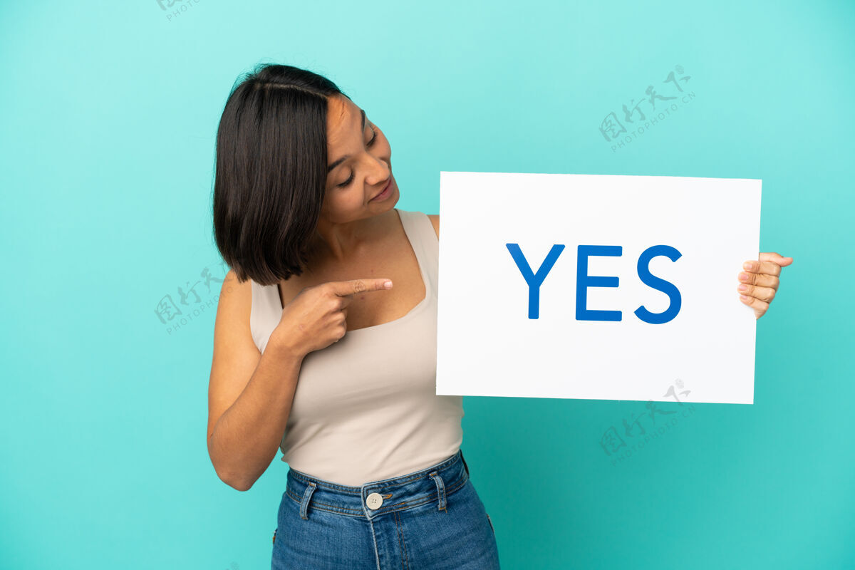 决定一个年轻的混血女 拿着一个写着“是”的标语牌 指着它 被隔离在蓝色的背景上信息女女孩