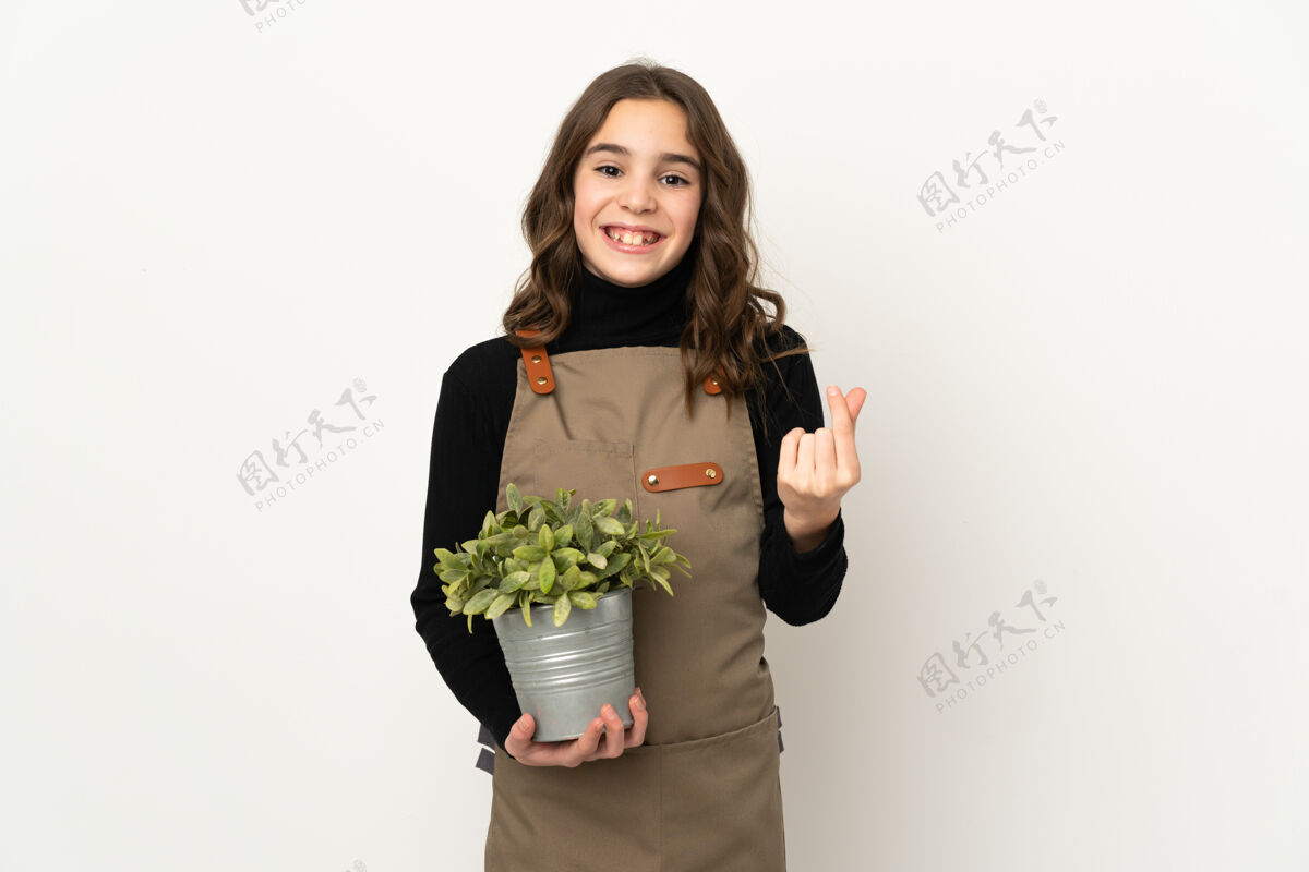 小小女孩抱着一株孤立在白色背景上赚钱的植物手势花小花盆