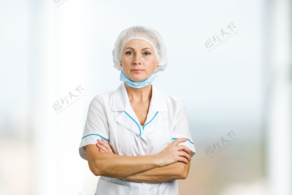 工人双臂交叉的女外科医生穿着白色制服的自信成熟的医生的画像专业女士绷带