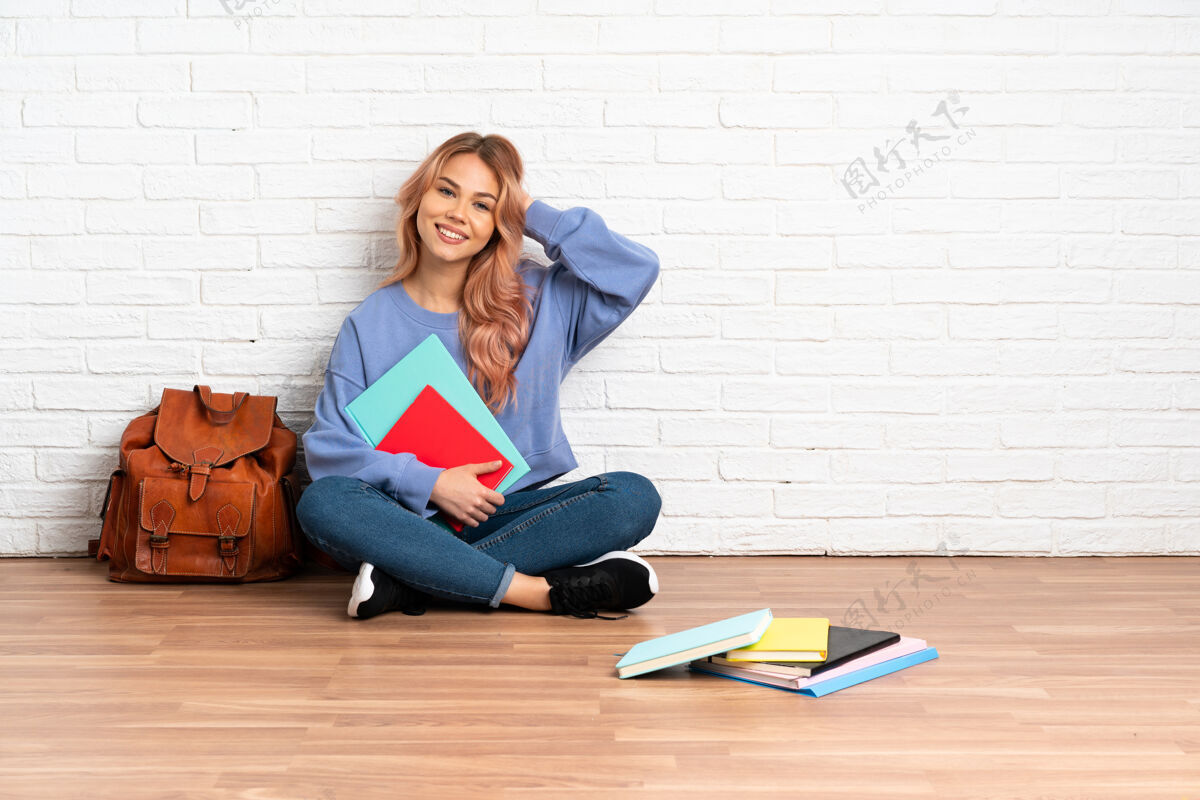 学习一个粉红色头发的女学生坐在地板上笑人教育背包