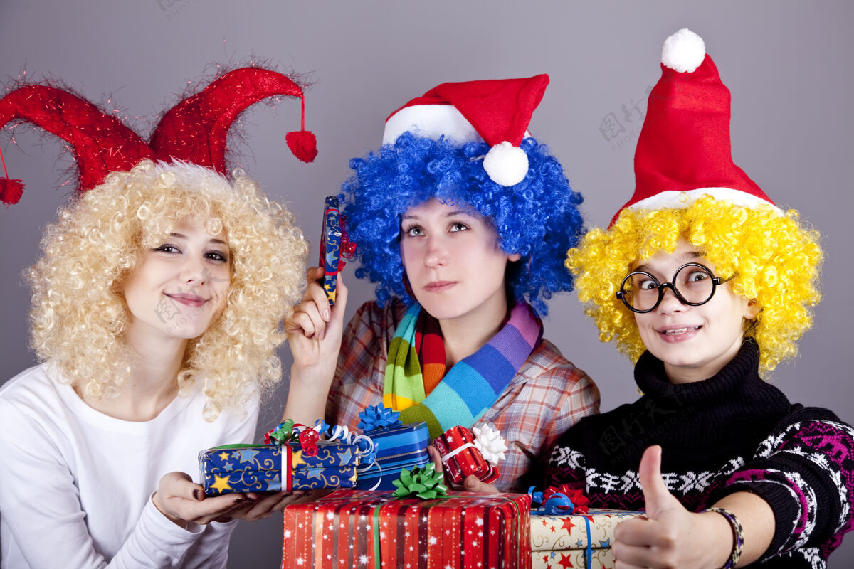 享受三个戴着滑稽帽子过圣诞节的女朋友礼品工作室射击圣诞老人节日举行