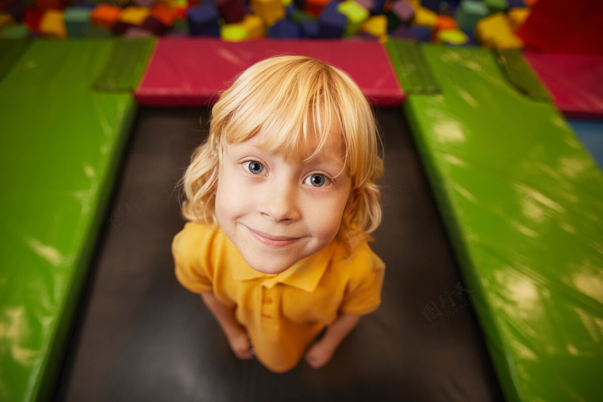 美丽可爱的小男孩在游乐园跳蹦床时看前面的画像快乐跳跃肖像