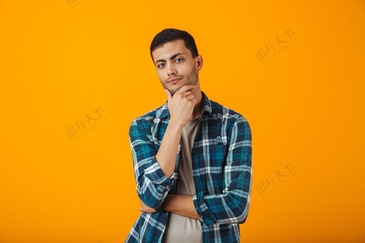 男人一个穿着格子衬衫的沉思的年轻人孤零零地站在橙色的墙上思想休闲风格