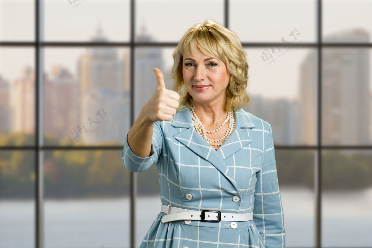 自信优雅成熟的女士抬起大拇指微笑的白皮女士抬起大拇指 站在办公室的窗户上欧洲心理学提高