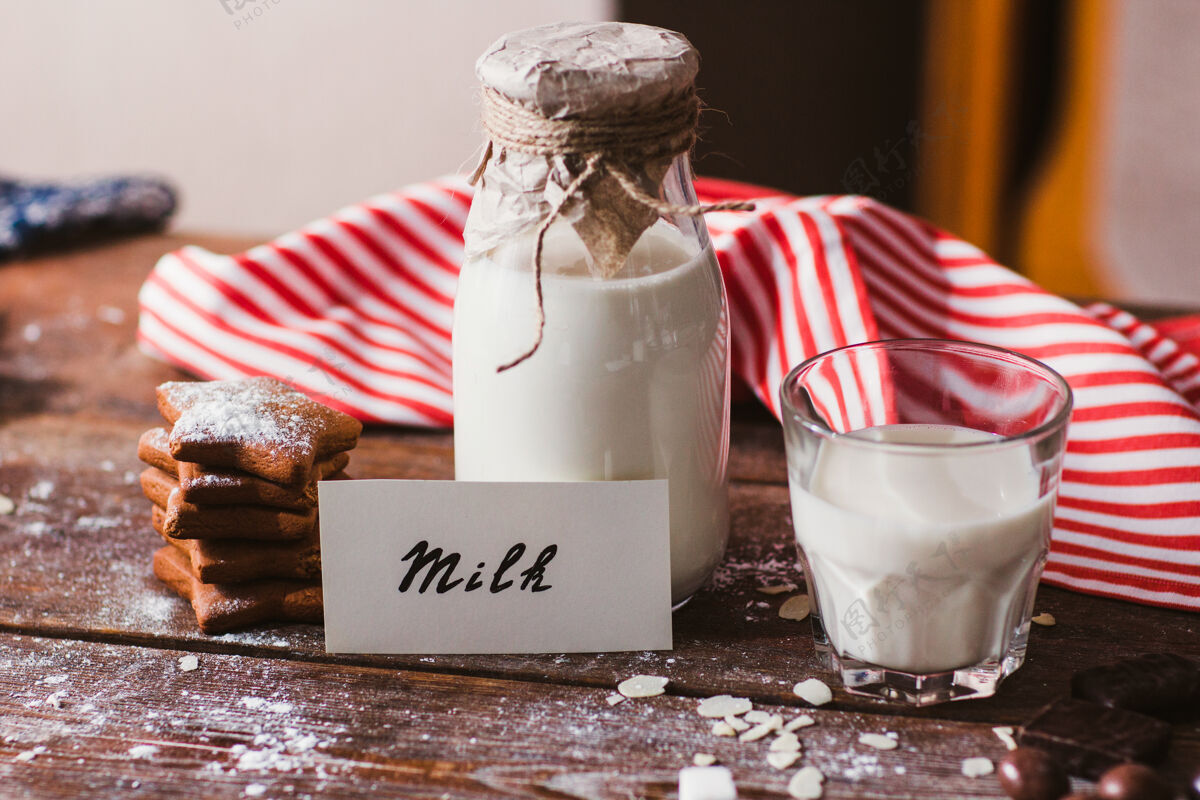 白色桌上放着一瓶一杯牛奶和饼干甜点食物罐子