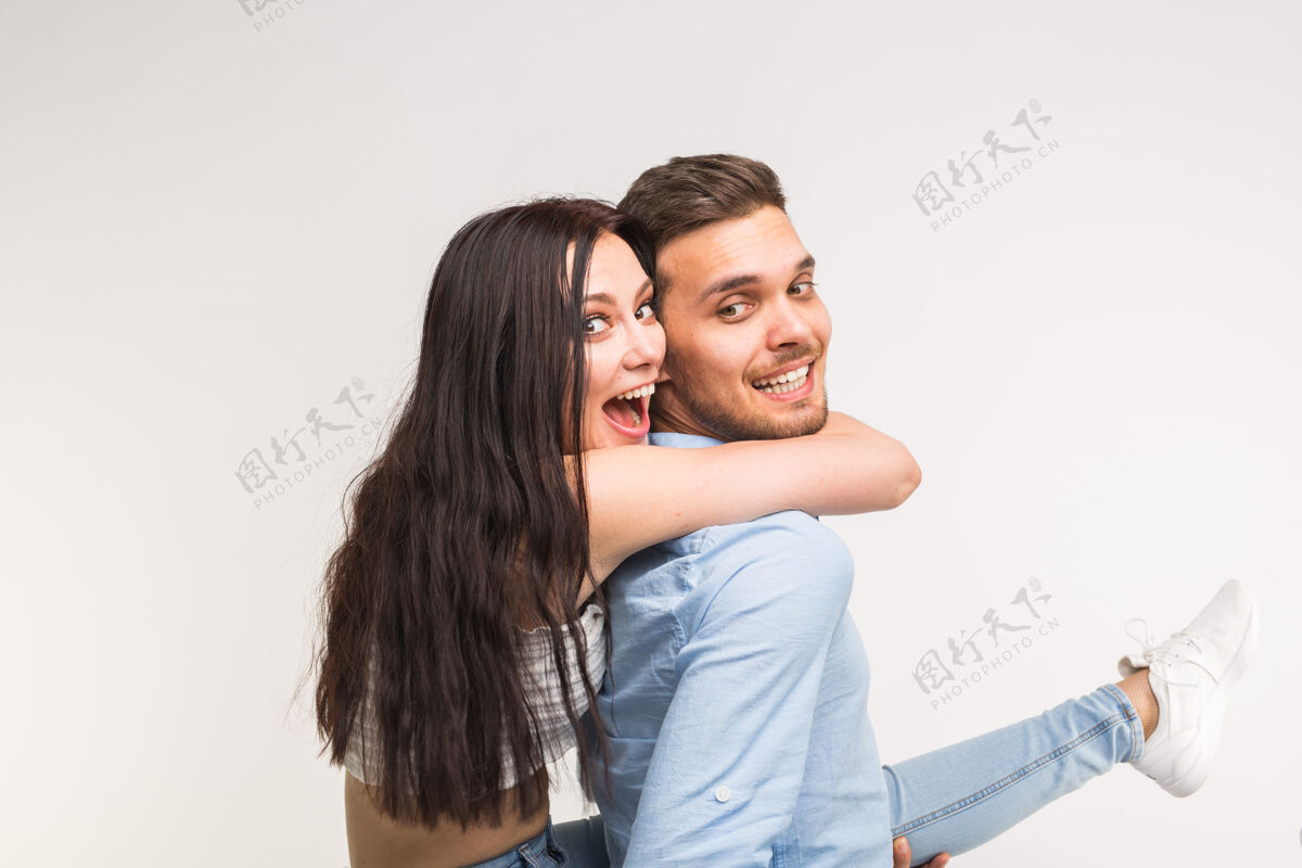 肩膀年轻的男人背着他的女朋友玩表情无忧无虑