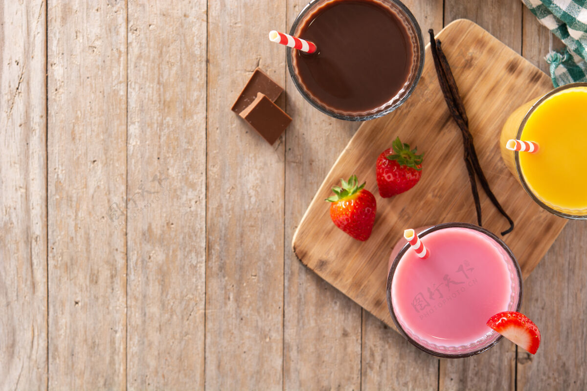 早餐巧克力 草莓和香草奶昔放在乡村木桌上稻草草莓美味