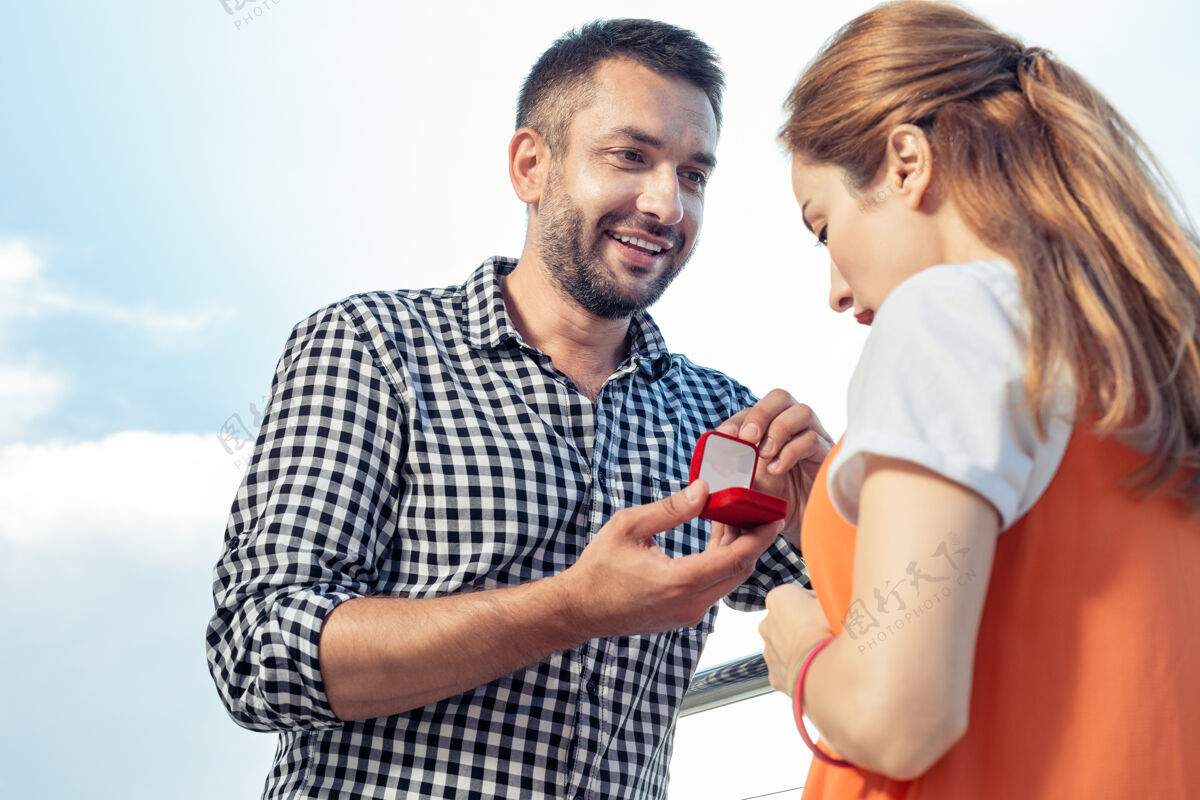 公寓订婚戒指快乐的好人在求婚的时候拿着戒指打开盒子屋顶男人关系