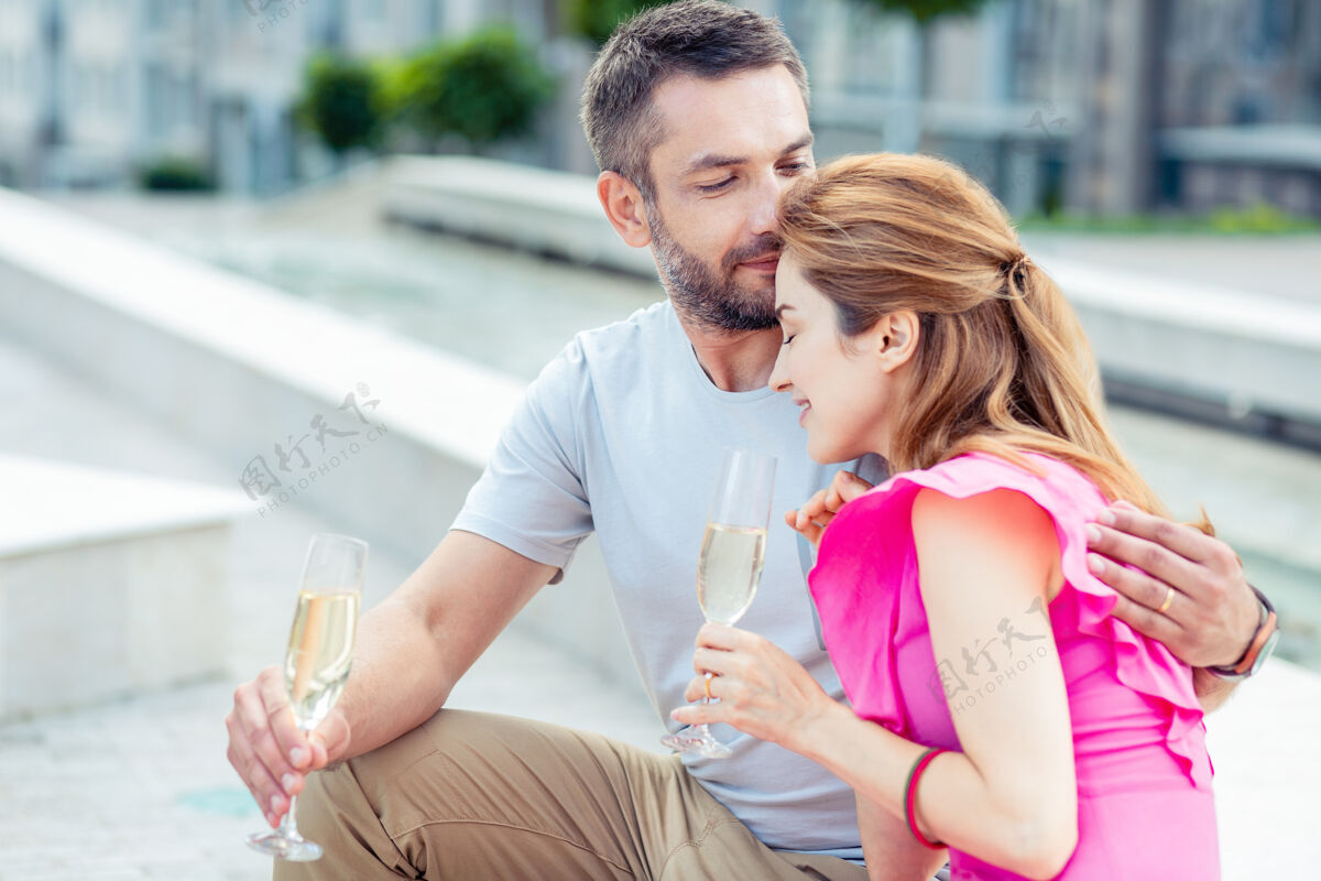 一起我的爱人 一个英俊的好男人一边抱着一杯香槟 一边拥抱他心爱的女朋友酒精休闲快乐