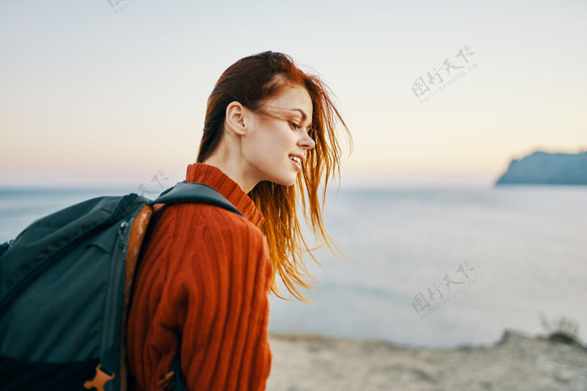 背包背着背包 穿着红色毛衣的女游客在沙滩上散步女人成人女人