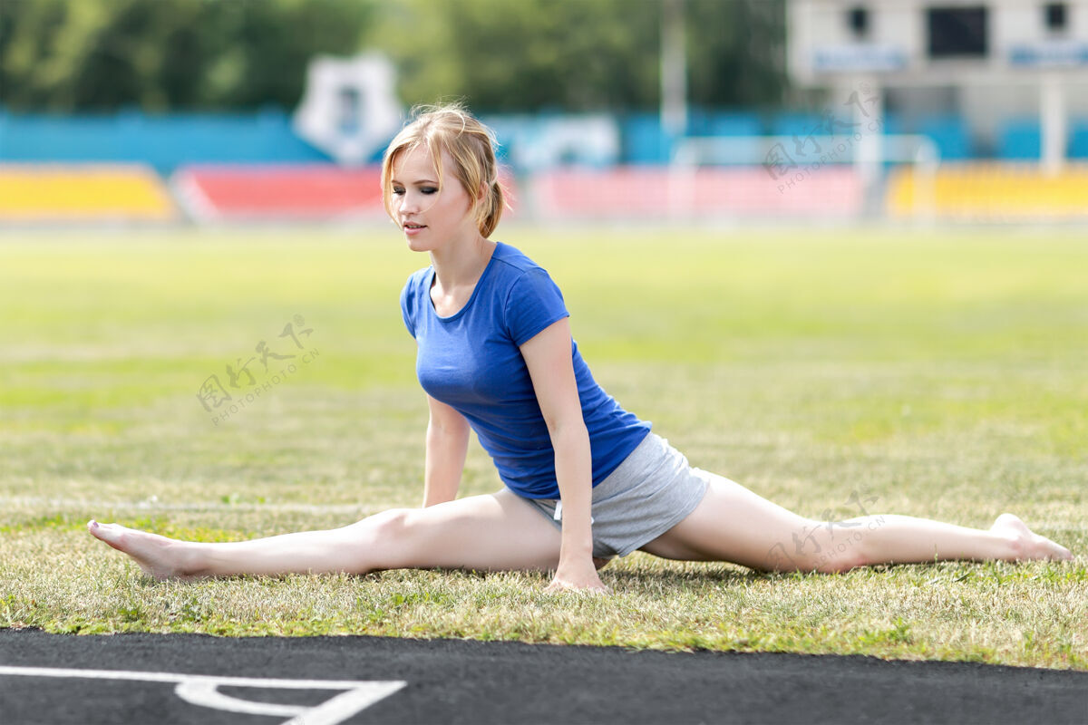 运动适合运动型女子做伸展运动 坐在体育场分裂人伸展形状