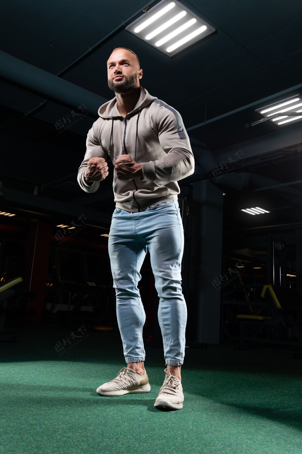 黑暗肌肉发达的男人穿着牛仔裤和运动衫在健身房摆姿势健身力量男人