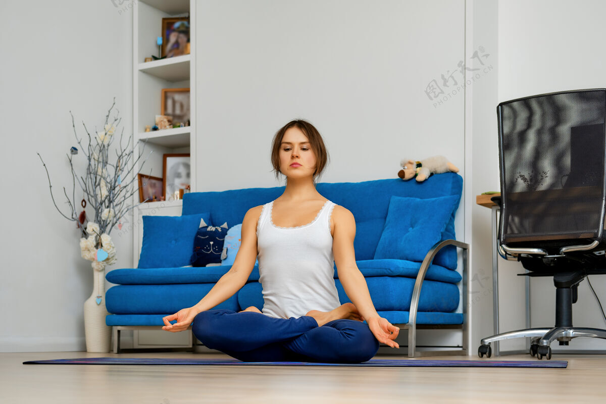 健康在家练习瑜伽的年轻女子坐在垫子上轻松地摆姿势活跃健身轻松