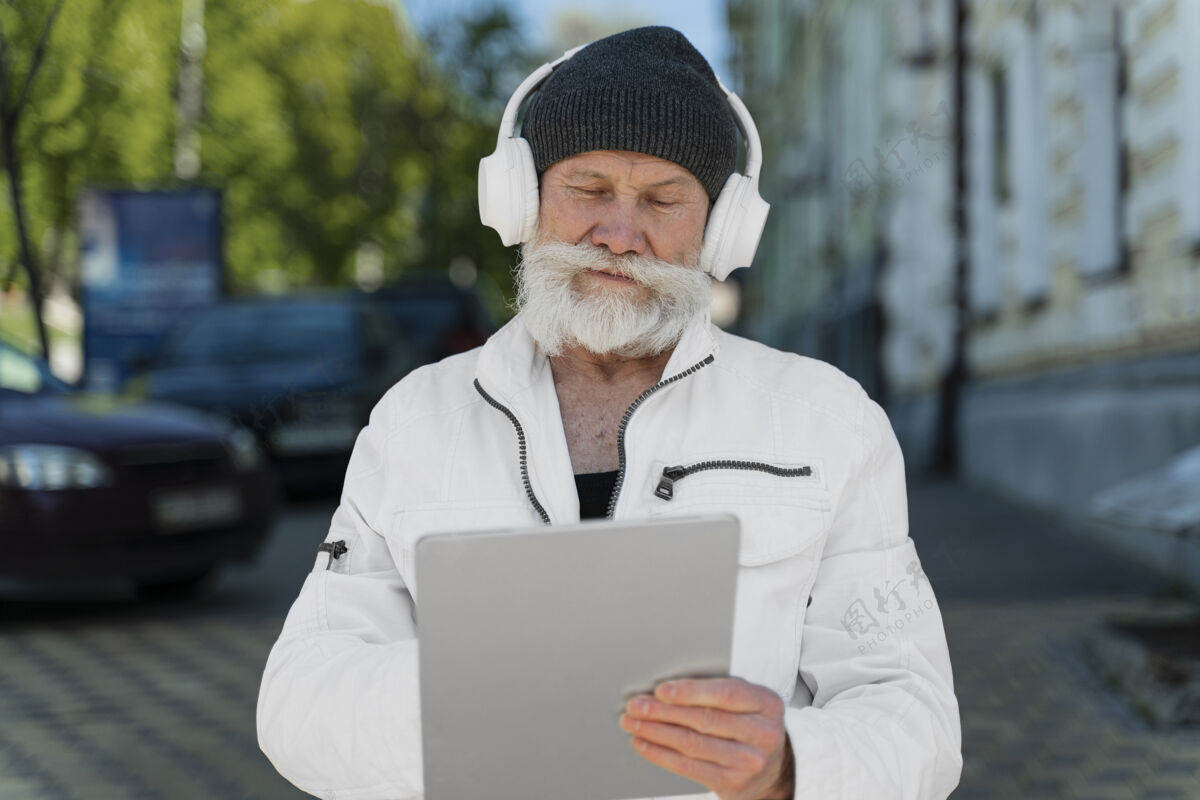 老年人戴着耳机和平板电脑的中枪男人老年人生活方式城市