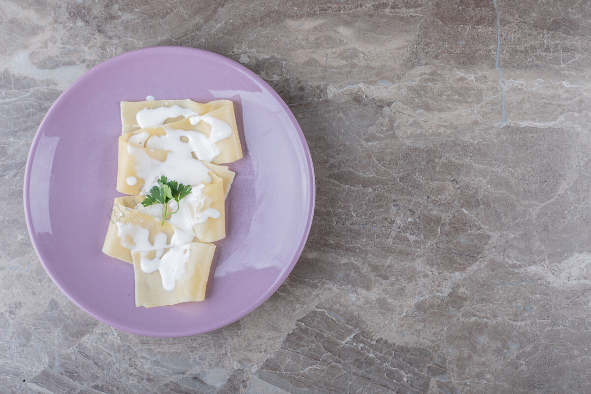 美味酸奶放在烤宽面条上 盘子上放绿色蔬菜 放在大理石表面美味绿色风味